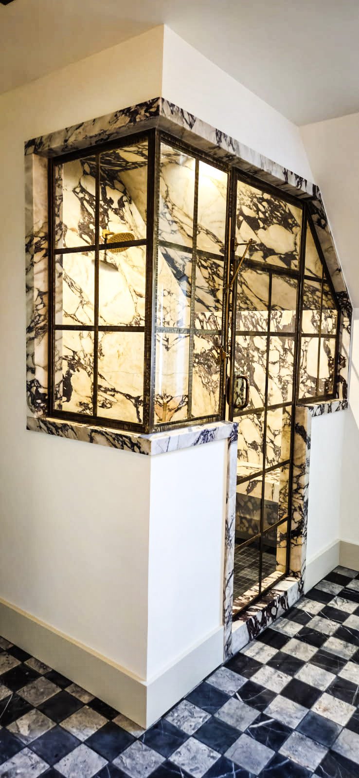 Brass-framed glass shower set in marble