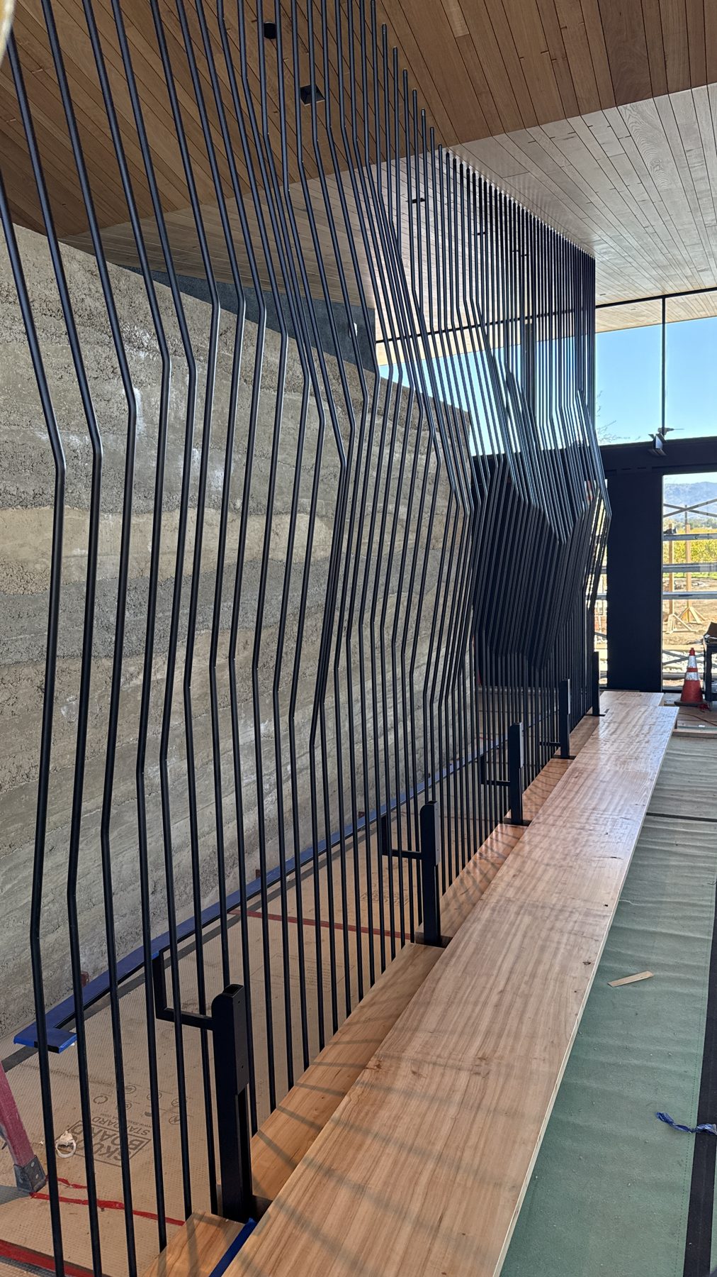 Black steel handrail and a wall of bent rod fins
